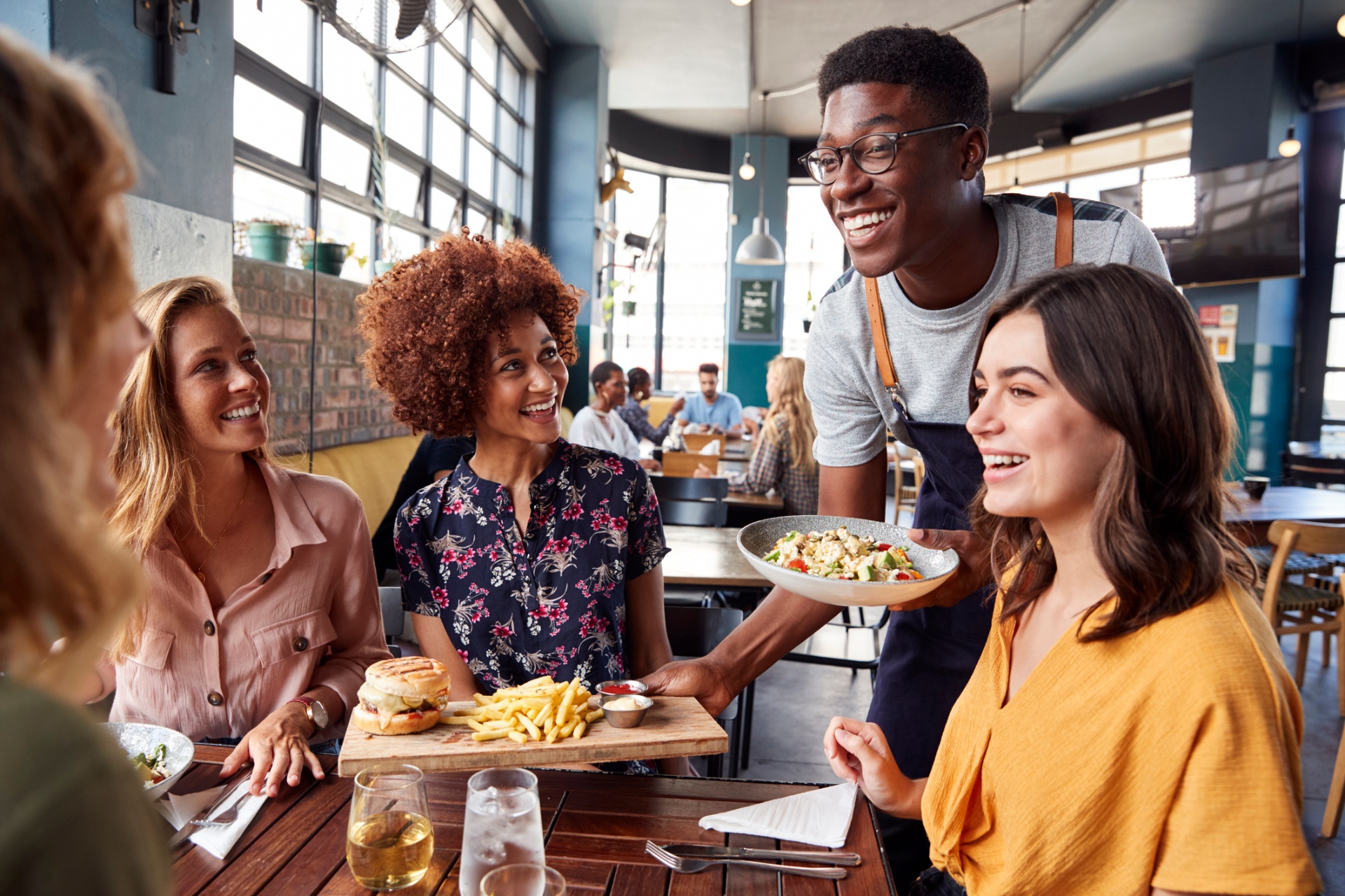Server delivering food to a full table of guests